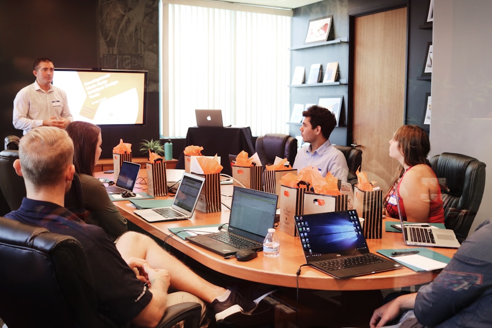 A trainer presenting to a room of professionals with laptops