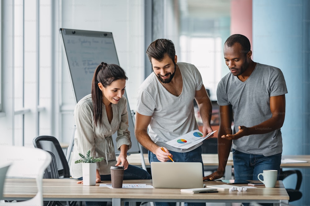 Three colleagues reviewing work together at a desk